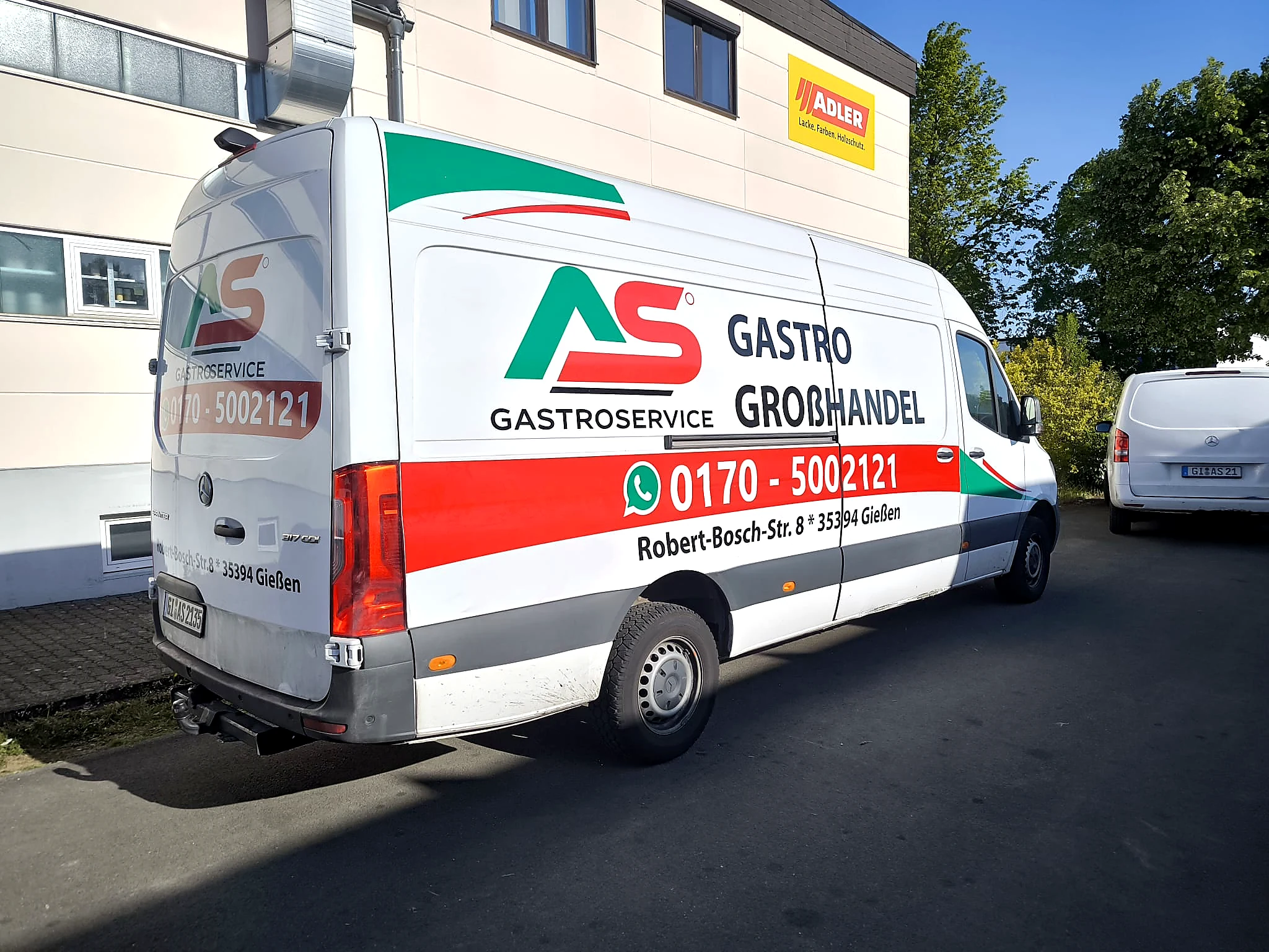 Beschrifteter AS-Gastroservice-Transporter mit markantem Logo, klarer Leistungsangabe und großer Telefonnummer