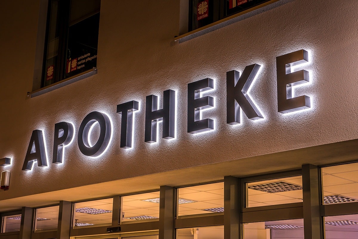 Rückleuchtende APOTHEKE Profilbuchstaben mit weißem Lichtsaum an einer Fassade bei Nacht